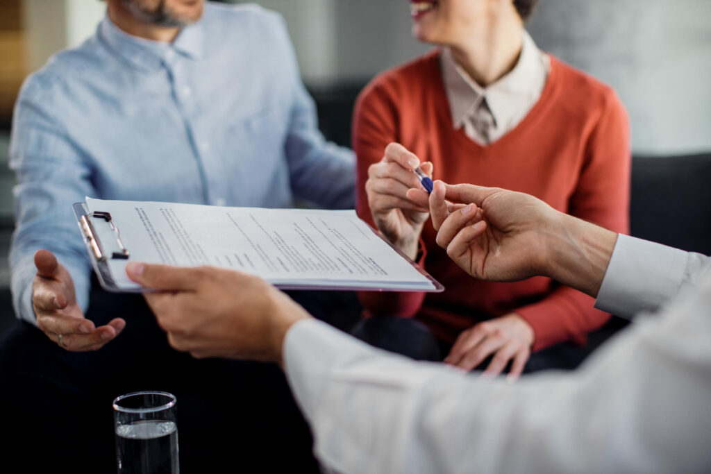 closeup-unrecognizable-couple-signing-contract-with-financial-advisor (1)
